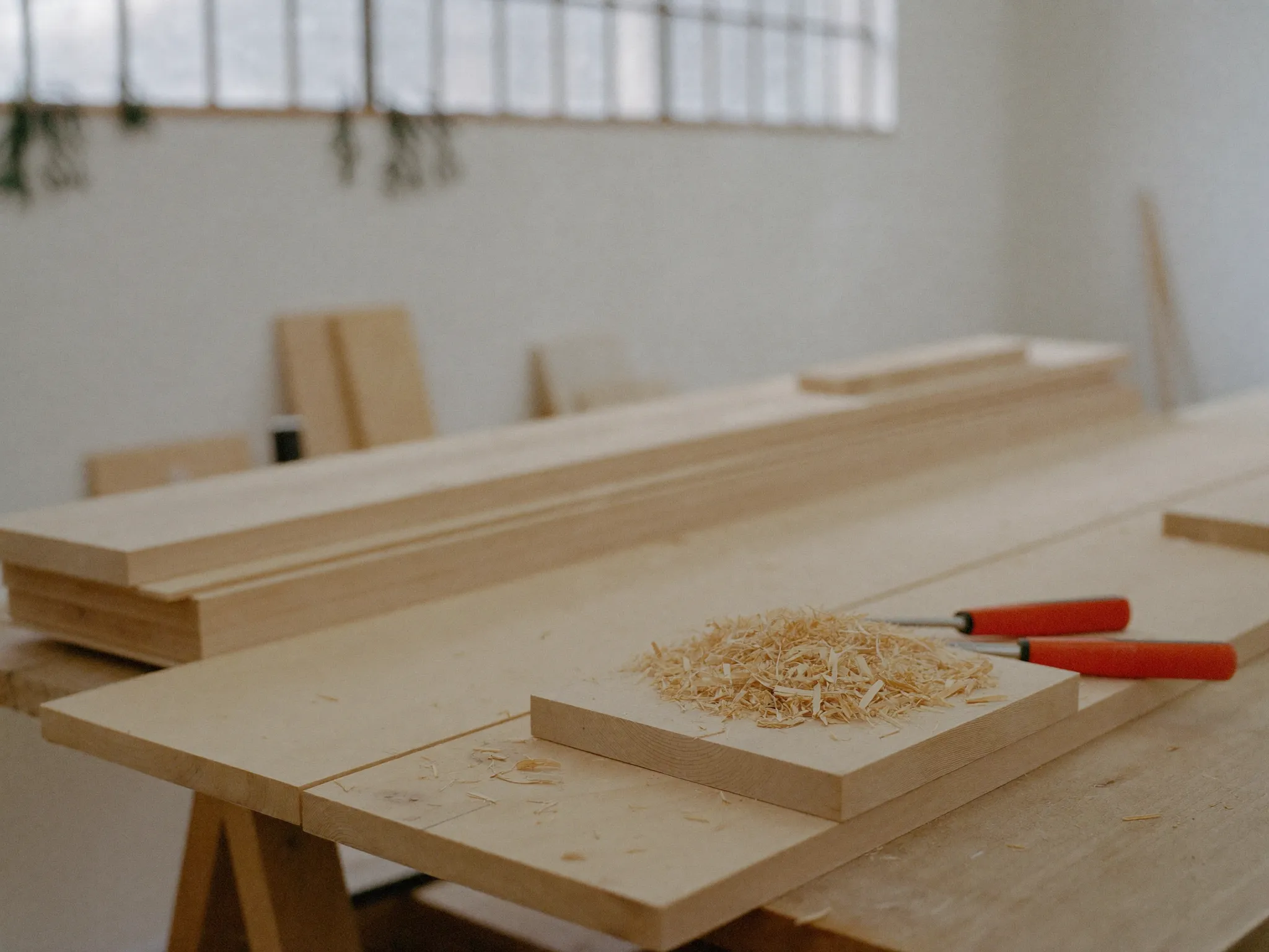 Gehobelte helle Holzbretter und Werkzeug auf der Werkbank